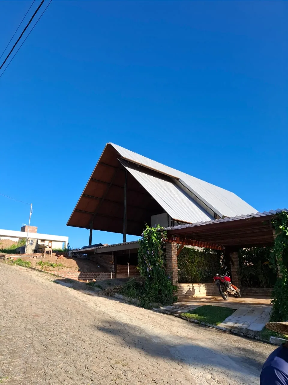 Chalé A-frame de alto padrão com grande telhado metálico de forte caimento e área coberta com pergolado, obra real