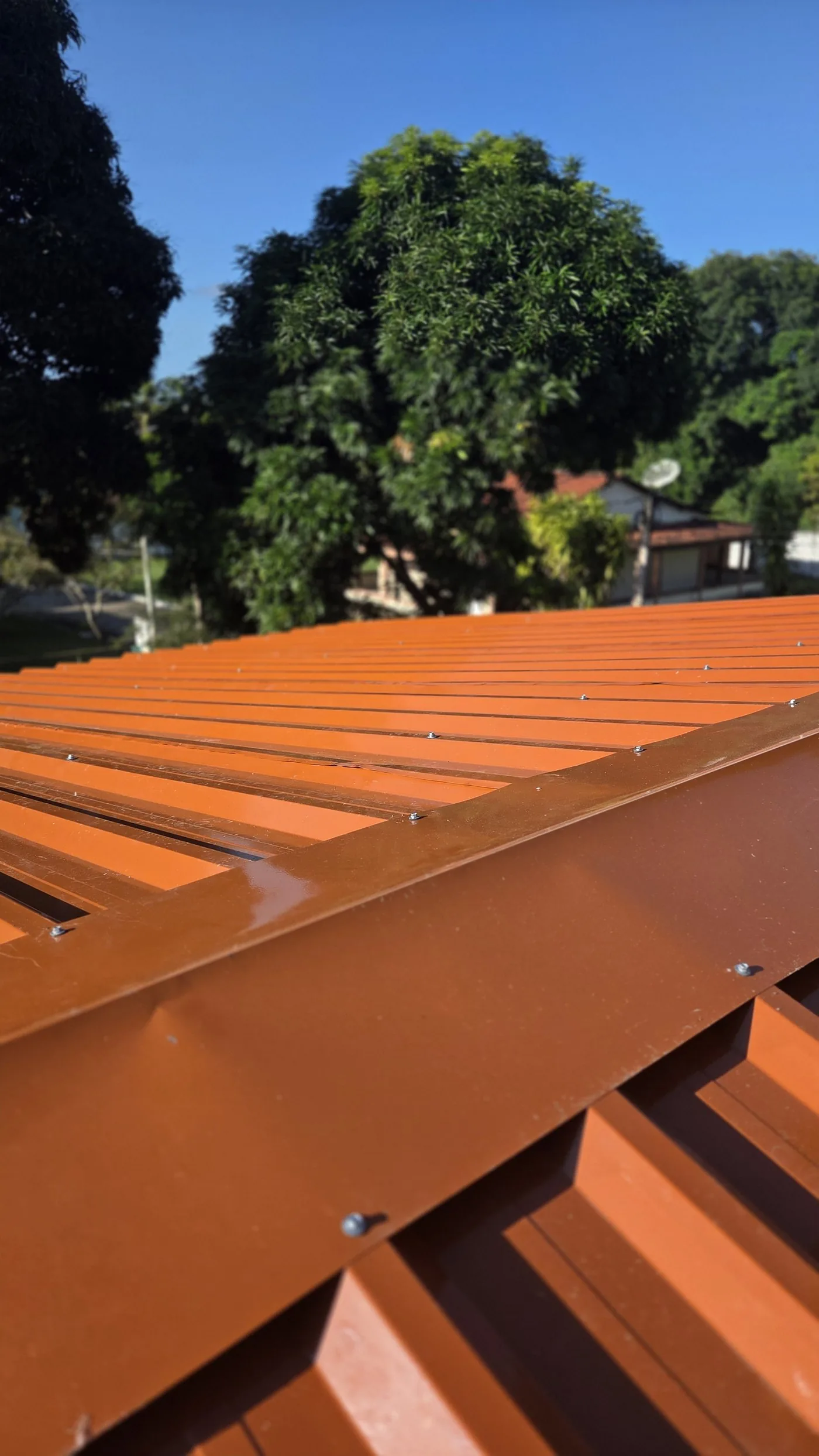 Cumeeira e fixação aparente de telhado em telha termoacústica Ecorenovar com acabamento terracota em pintura eletrostática
