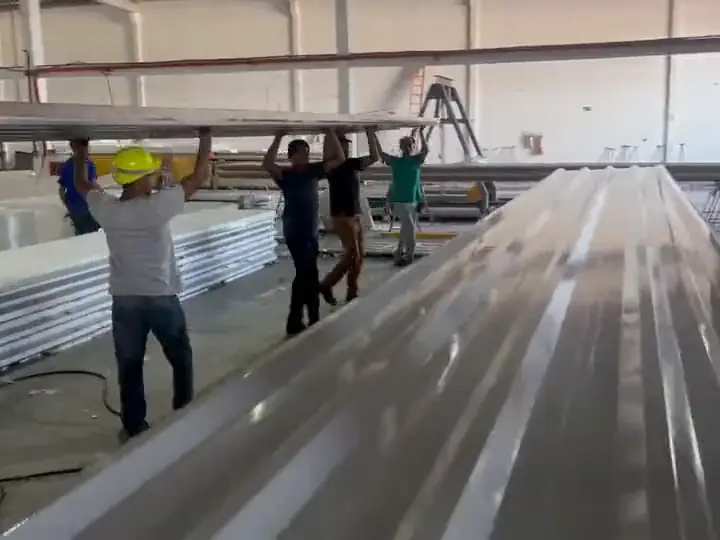 Equipe da Ecorenovar carregando telha termoacústica comprida dentro da fábrica
